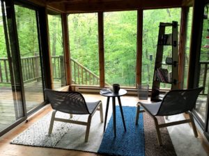 Reading room with large windows and 2 chairs overlooking the woods
