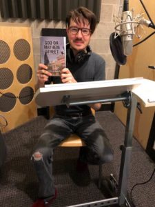 Rob Doyle in the sound booth holding his copy of God on Mayhem Street