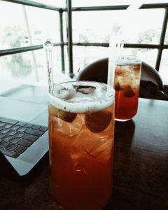 Two mixed drinks next to an open computer