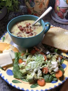 Bowl of bacon leek soup, salad, bread and cheese