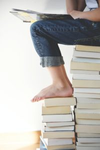 Person sitting on two stacks of books reading