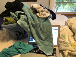Basket of laundry overflowing on to Kristin's laptop