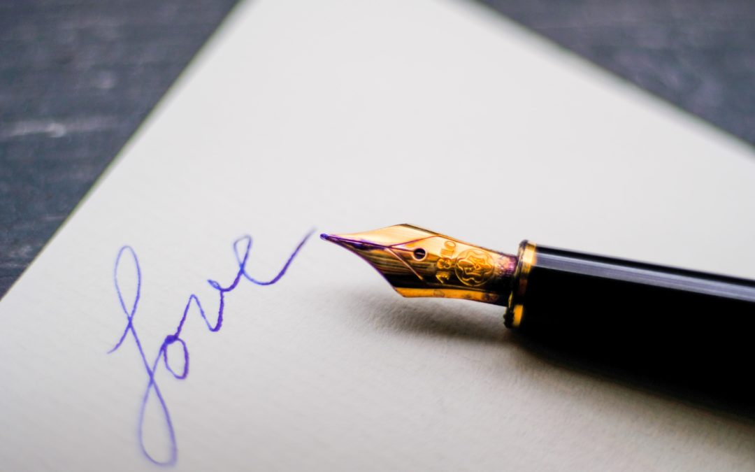 A fountain pen on a piece of paper with the word Love written on it