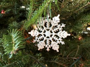 Snowflake ornament hanging in evergreen tree