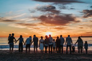 People holding hands on the beach gazing into the sunset