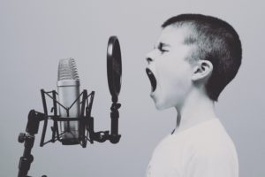 A young boy shouting into an old-fashioned microphone