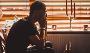 Sitting man with his elbows on his knees, rubbing his face