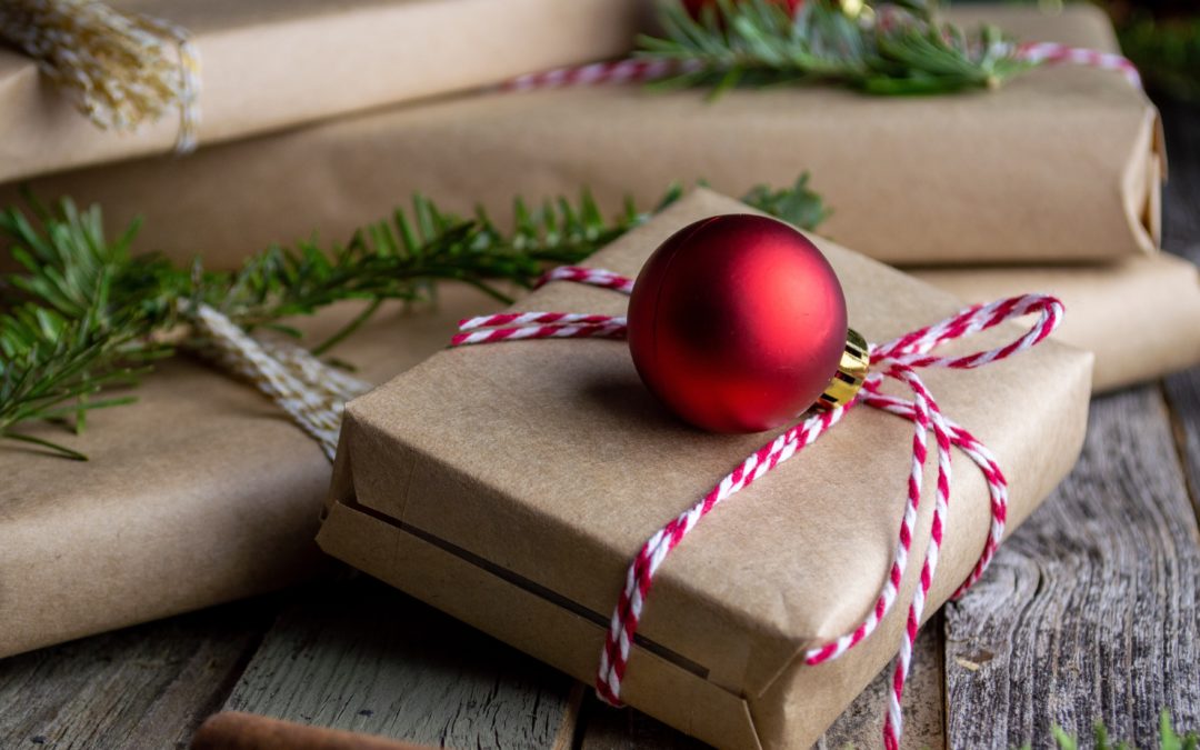 Brown paper packages with red ornaments and sprigs of evergreen