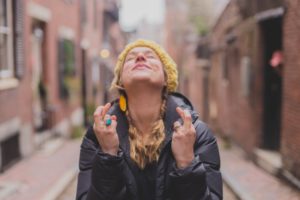 Woman with her eyes closed and her fingers crossed