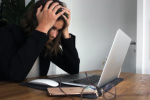 A woman staring at a computer with her head in her hands