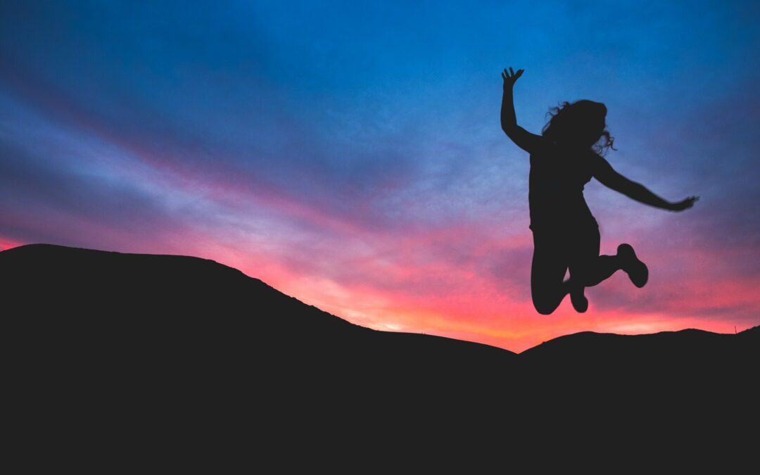 Silhouette of a woman jumping in the sunset.
