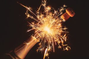 Cork and sparks flying out of a champagne bottle