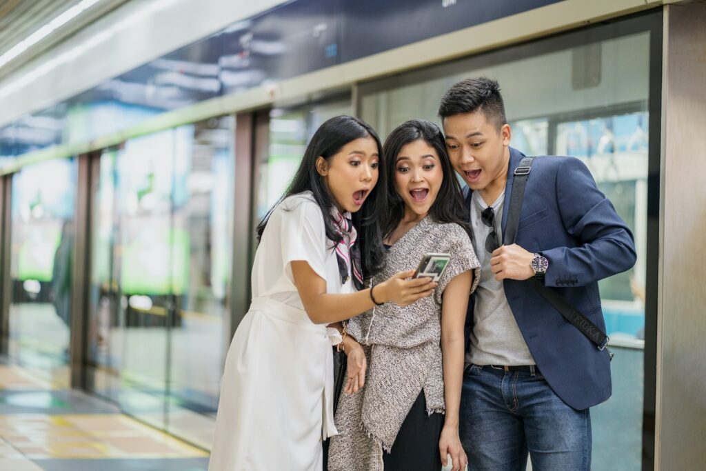Two excited women and one man looking at a phone