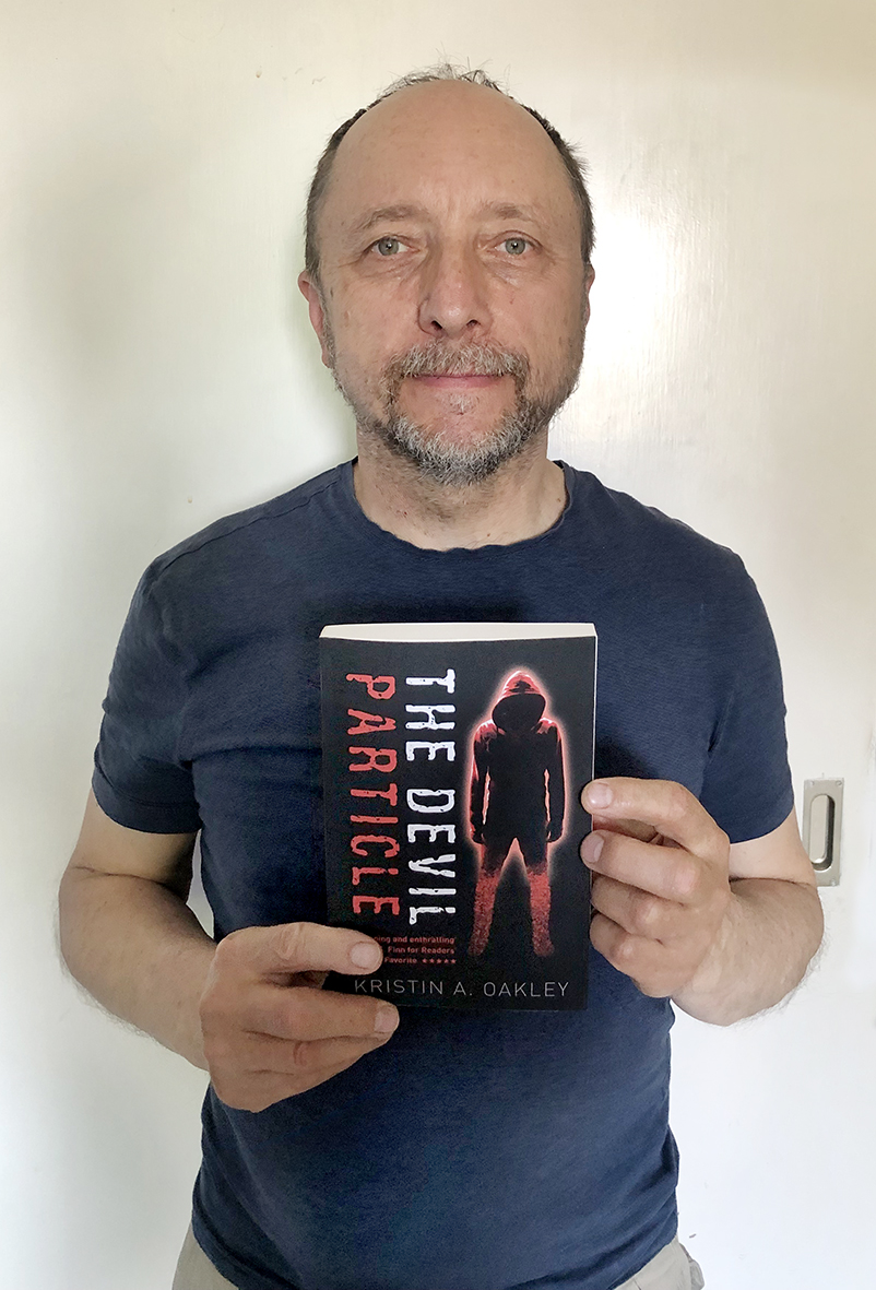 Cover designer Patrick Knowles holding his copy of The Devil Particle