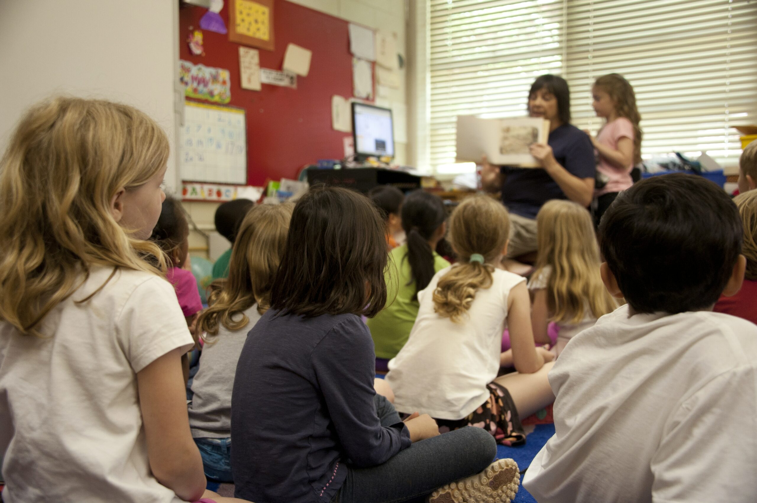 Children listening to a teacher read a book