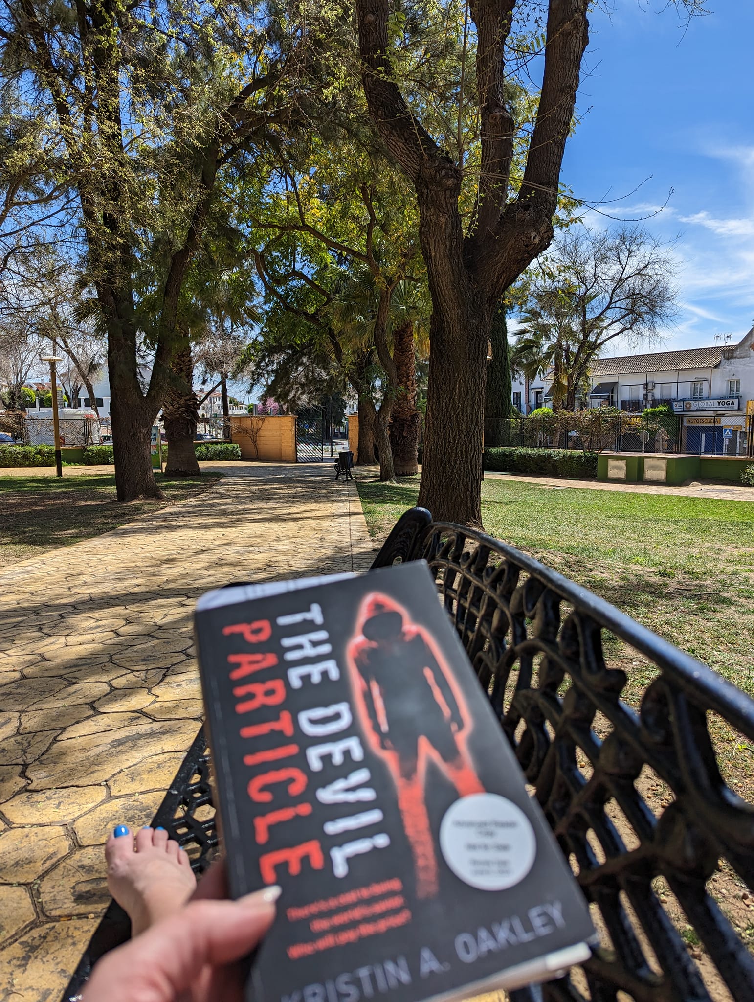 Corina Rogers holding book while sitting on a park bench