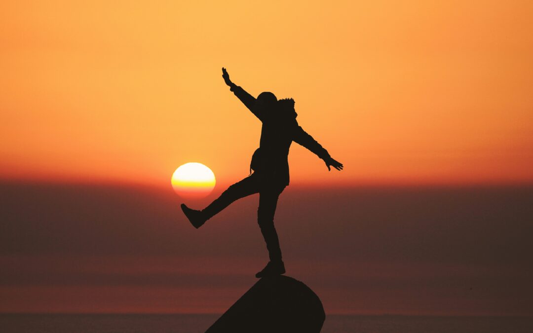 Person on a mountaintop kicking the setting sun